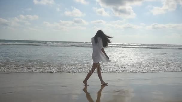 Lycklig kvinna promenader och spela på stranden nära havet. Ung vacker flicka njuter av livet och att ha kul på havet. Sommarsemester eller semester. Exotiska landskap i bakgrunden. Slow motion — Stockvideo