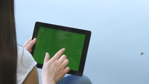 Женские руки с цифровым планшетным ПК с зеленым экраном, сидя на деревянном причале у озера . — стоковое видео
