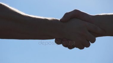 Mavi gökyüzü arka plan üzerinde iki tanınmaz kas beyaz adamın dostu el sıkışma. Erkek silah açık sallayarak. İki güçlü adam dışında firma el sıkışma sahip. Takım çalışması ve dostluk. Yakın çekim