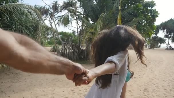 Folge mir, wie eine junge Frau ihren Freund am Ufer des Meeres zieht. Mädchen hält männliche Hand und läuft am tropischen exotischen Strand zum Meer. Sommerurlaub oder Urlaub. Standpunkt. Zeitlupe — Stockvideo