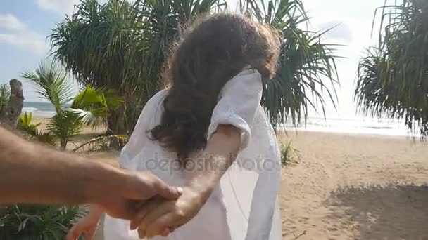 Girl holding male hand and running on tropical exotic beach to the ocean. Follow me shot of young woman pull her boyfriend on the sea shore. Summer vacation or holiday. Point of view. POV Slow motion — Stock Video