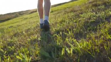 Mavi gökyüzü arka plan üzerinde yeşil tepeden koşan genç adam. Erkek atlet doğada günbatımında koşu. Koşu spor atlet açık parlama ile gündoğumu, yokuş yukarı. İkinci el eğitim. Yakın çekim
