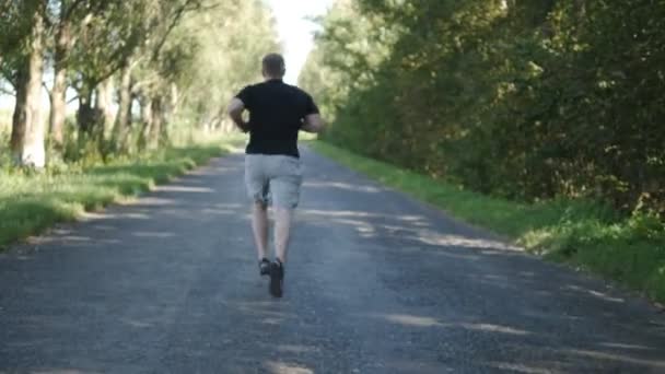 Дорослий чоловік бігає на відкритому повітрі на лісовій стежці. Старий біжить на відкритому повітрі в природі — стокове відео