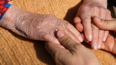 Yaşlı bir çift el büyükanne açık, rahatlatıcı bir genç erkek el yakın çekim.