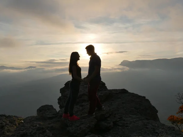 Silhouette di giovane coppia in piedi su una montagna e guardando l'un l'altro su uno sfondo bellissimo tramonto. Amore di ragazzo e ragazza . — Foto Stock