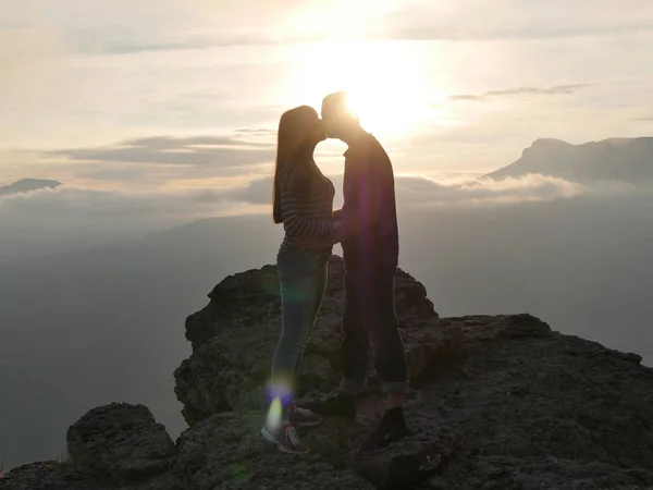 Силуети молодої пари стоять на горі і дивляться один на одного на красивому фоні заходу сонця. Любов хлопця і дівчинки . — стокове фото