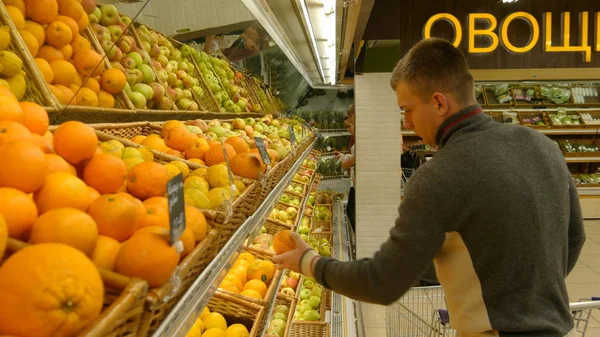 쇼핑 카트를 가진 남자는 sypermarket에 오렌지를 선택 — 스톡 사진