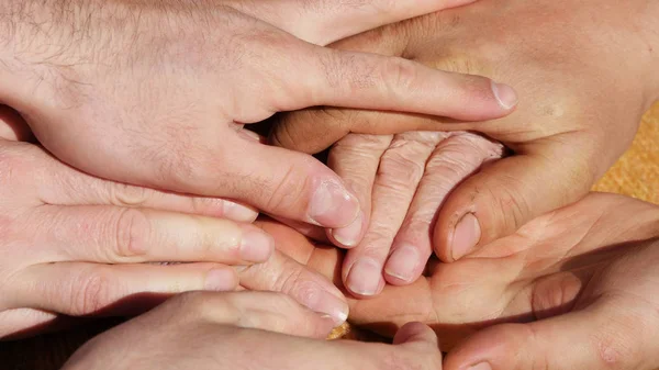 Many hands comforting a old pair of hands outdoor. — Stock Photo, Image