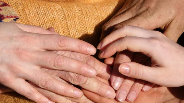 Many hands comforting a old pair of hands outdoor. — Stock Photo, Image