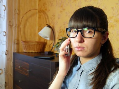 Evde cep telefonuyla konuşan neşeli genç bir kadın.