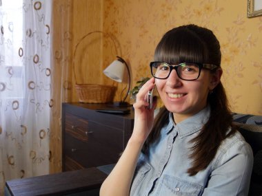 Evde cep telefonuyla konuşan neşeli genç bir kadın.