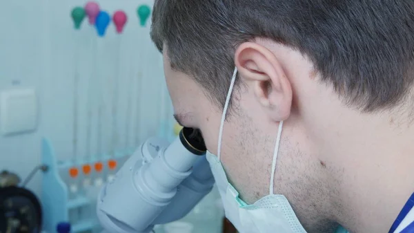 Doctor looking through the eyepiece of a microscope. — Stock Photo, Image