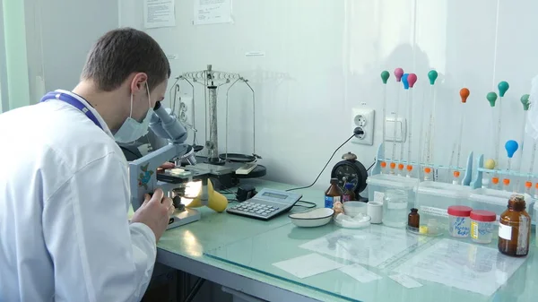 Joven médico masculino viendo a través del microscopio — Foto de Stock