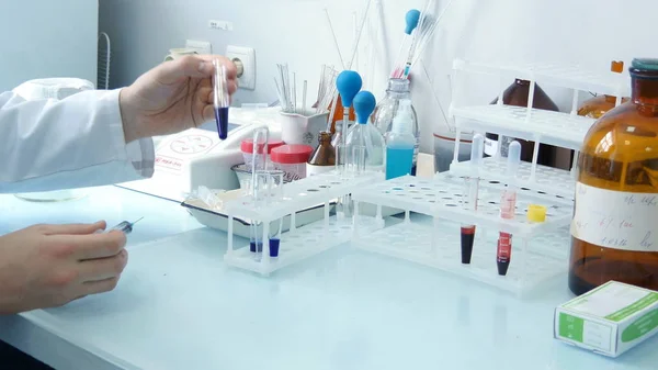 Arzt betrachtet blaue Flüssigkeit im Reagenzglas — Stockfoto