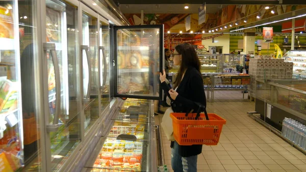 Молодая женщина покупает молочные или холодильные продукты в супермаркете — стоковое фото