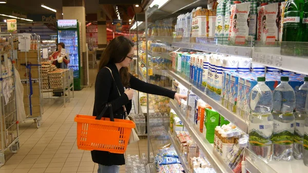 genç kadın satın alma süt veya süpermarkette buzdolabında yiyecek
