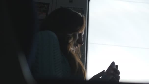 Молода дівчина телефонує під час їзди в поїзді. Жінка подорожує залізницею і розмовляє по смартфонах. Жінка дивиться на вікно і говорить на мобільний телефон — стокове відео