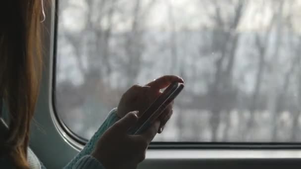 Chica joven que viaja en un tren y el uso de teléfono móvil. Hermosa mujer envía un mensaje desde el teléfono inteligente. Chica atractiva charlando con amigos. De cerca. — Vídeo de stock