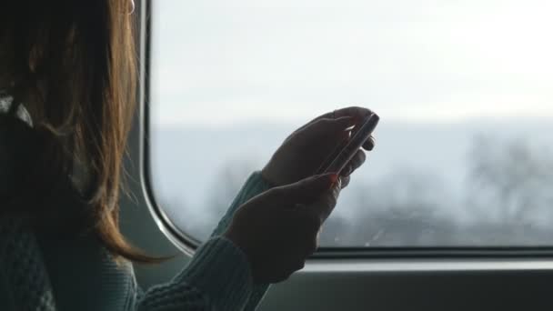 Genç kız bir tren seyahat ve istimal hareket eden telefon. Güzel kadın smartphone--dan bir ileti gönderir. Çekici kız arkadaşlarınızla sohbet. Yakın çekim — Stok video
