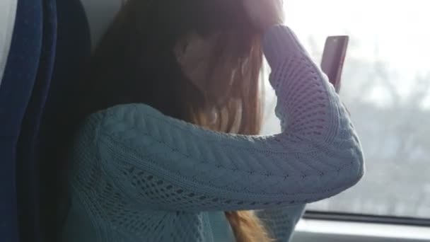 Menina olhando para o telefone como espelho para omitir seu cabelo durante a viagem na estrada de ferro. Mulher bonita monta no trem, olhando para o smartphone e corrigir seu penteado. Mulher fazendo selfie — Vídeo de Stock