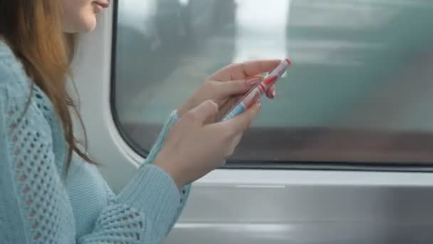 Genç kız bir tren seyahat ve istimal hareket eden telefon. Güzel kadın smartphone--dan bir ileti gönderir. Çekici kız arkadaşlarınızla sohbet. Tren pencerede geçiyoruz. Yakın çekim — Stok video
