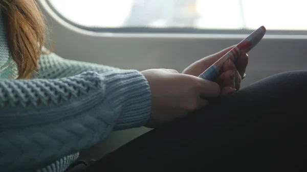 Junges Mädchen, das in einem Zug unterwegs ist und Mobiltelefone benutzt. schöne Frau sendet eine Nachricht vom Smartphone. attraktive Mädchen im Chat mit Freunden — Stockfoto