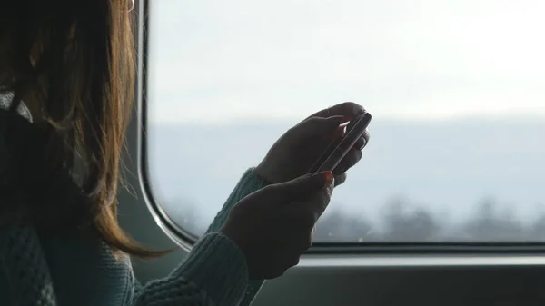 Junges Mädchen, das in einem Zug unterwegs ist und Mobiltelefone benutzt. schöne Frau sendet eine Nachricht vom Smartphone. attraktive Mädchen im Chat mit Freunden. Nahaufnahme — Stockfoto