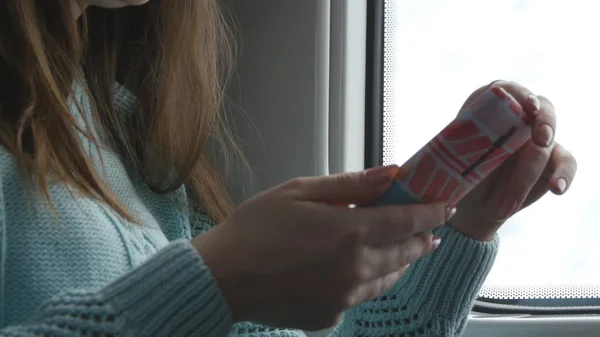 Junge Frau, die in einem Zug unterwegs ist und Mobiltelefone benutzt. Die weibliche Hand sendet eine Nachricht vom Smartphone. Arm von Mädchen, die mit Freunden chatten. Nahaufnahme — Stockfoto