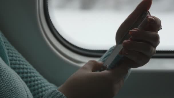 Mujer joven viajando en un tren y utilizando el teléfono móvil. La mano femenina envía un mensaje desde el teléfono inteligente. Brazo de chica charlando con amigos. De cerca. — Vídeos de Stock