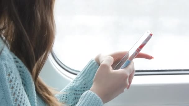 Fiatal nő utazik a vonaton, és a mobiltelefon használata. Női kéz küld egy üzenetet a smartphone. Kar, lány, csevegni a barátaival. Közelről — Stock videók