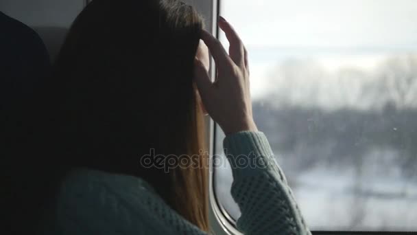 Jonge vrouw op zoek op venster tijdens het rijden op de trein. Profiel van:: aantrekkelijk meisje reizen aan spoorweg. Slow motion — Stockvideo