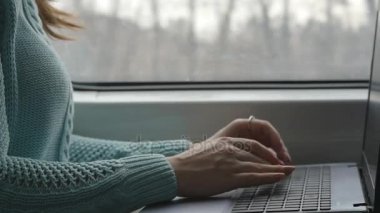 Genç kız bir tren seyahat ve dizüstü bilgisayar kullanarak. Erkek tipik dizüstü klavye üzerinde demiryolu üzerinde sürme sırasında eller. Çekici kadın arkadaşlarınızla sohbet. Yavaş hareket kapatmak