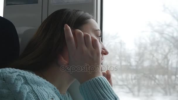 Giovane donna che guarda sul finestrino durante la guida in treno. Profilo di attraente ragazza che viaggia su ferrovia. Rallentatore Close up — Video Stock