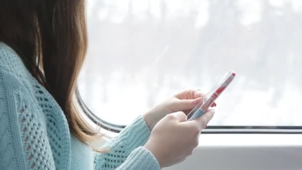 Chica joven que viaja en un tren y el uso de teléfono móvil. Hermosa mujer envía un mensaje desde el teléfono inteligente. Las manos femeninas charlando con amigos. Primer plano: cámara lenta — Vídeo de stock