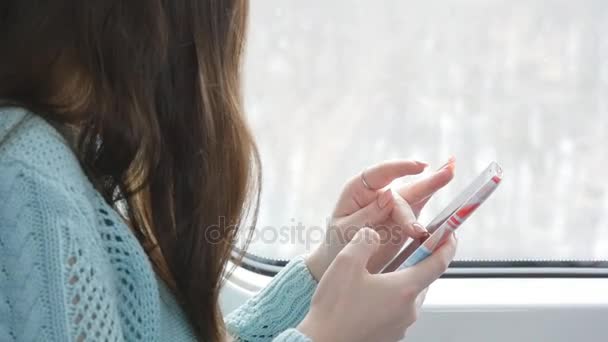 Genç kız bir tren seyahat ve istimal hareket eden telefon. Güzel kadın smartphone--dan bir ileti gönderir. Arkadaşlarınızla sohbet eller. Yavaş hareket kapatmak — Stok video