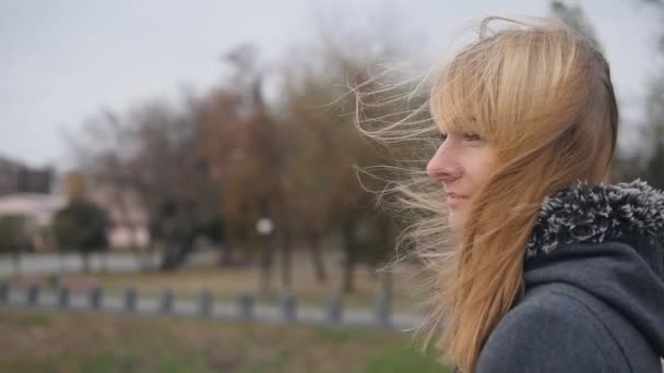 Fiatal lány állt az utcán, és a haja, csapkodott a szélben. Lassított felvétel — Stock videók