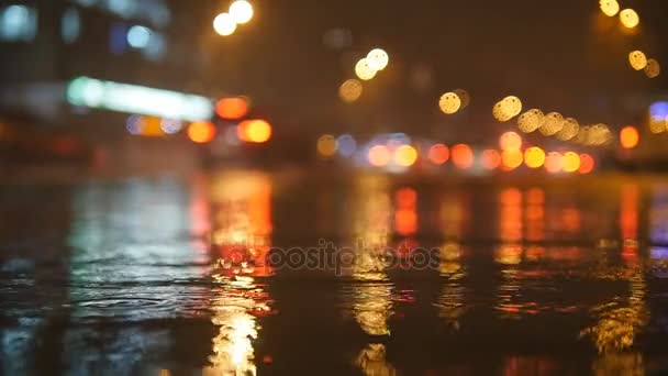 Colorful traffic lights bokeh circles reflecting in water on night city street with small raindrops. Slow motion video — Stock Video