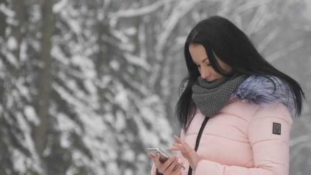 Молодая красивая девушка стоит на улице и использует свой телефон для чата — стоковое видео