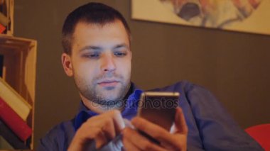 Genç yakışıklı bir kafede oturuyor ve haber kadar onun smartphone seçer