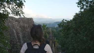 Genç kadın uzun yürüyüşe çıkan kimse dağ ve yükseltilmiş elleri yukarı ulaşan sırt çantası ile. Güzel Kanyon kenarında duran, zaferle yukarı silah outstretching kadın turist. Ağır çekim arka geri görüntülemek