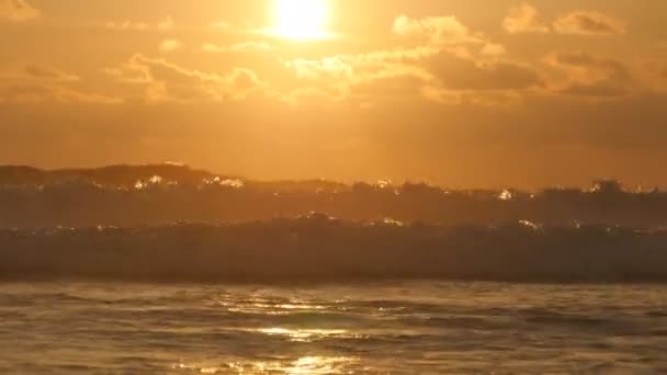 Wunderschöne goldene Meereswellen bei Sonnenuntergang. Orangefarbener Sonnenaufgang, der sich im Meerwasser spiegelt. Starke Flut mit Wellen plätschert an einem windigen Tag am Abend. Natur-Hintergrund hautnah — Stockvideo