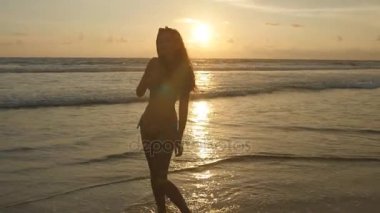 Uzun saçlı çekici seksi kız baştan çıkarıyor ve okyanus kıyısında güneş doğarken poz. Kendisi ile sunset bulvarında denize yakın arama bikini güzel ve genç birbayan. Erkek sahilde hayattan zevk