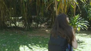 Mutlu kız sırt çantası ile yeşil orman yürüyüş ve eğleniyor. Gidiş ve tropikal orman iplik genç güzel kadın. Özgürlük seyahat kavramı. Arka arkadan görünüm