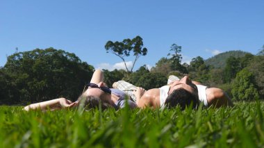 Genç çift, park yeşil çim üzerinde yalan ve rahatlatıcı. Adam ve kadın çayır, doğa üzerinde oturuyordu. Kız ve erkek manzaraya bakarak ve yaz tatili zevk. Arka geri düşük görüş açısı