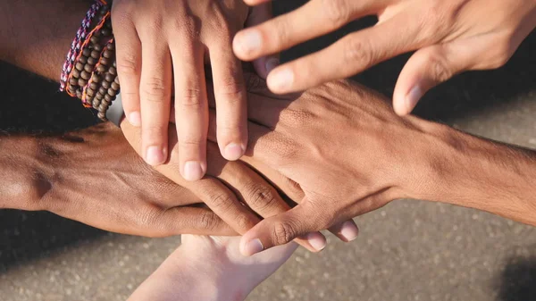 Bras de toutes les races et couleurs empilés un par un dans l'unité et le travail d'équipe, puis soulevés. Beaucoup de mains multiraciales se réunissant au centre d'un cercle, puis acclamer. Gros plan extérieur — Photo