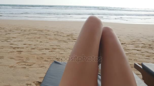 Hlediska mladá žena ležící na lehátko, moře a opalování. Ženské nohy na lehátko relaxační a těší během letní dovolené na pláži u oceánu. Úpatí dívka na resort. Detailní záběr Pov
