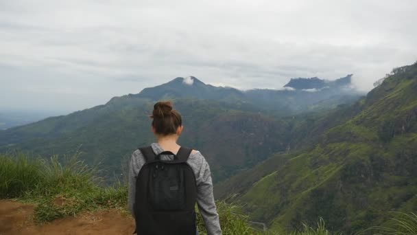 Turista mujer corriendo al borde del hermoso cañón, extendiendo victoriosamente los brazos hacia arriba. Joven excursionista con mochila que llega a la cima de la montaña y levanta las manos. Cámara lenta Primer plano — Vídeo de stock