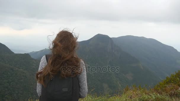 Mladé samice turistické s batohem, užívat si krásný výhled na horách. Rumunsko, stojící na okraji krásného kaňonu a při pohledu na povahu. Slow motion blízko chvostu pohled zezadu — Stock video