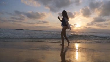 Genç güzel kız hayattan zevk ve deniz sahilinde eğleniyor. Yürüyüş ve Okyanusu yakınlarındaki sahilde oynarken mutlu bir kadın. Yaz tatili ya da tatil. Arka plan, doğa manzara. Ağır çekim