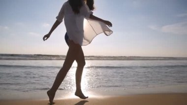 Yürüyüş ve Okyanusu yakınlarındaki sahilde oynarken mutlu bir kadın. Genç güzel kız hayattan zevk ve deniz sahilinde eğleniyor. Yaz tatili ya da tatil. Arka plan, doğa manzara. Ağır çekim